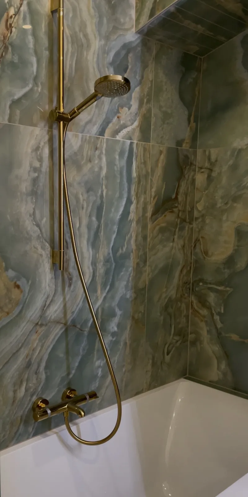 Badewanne mit goldener Armatur und Natursteinoptik, Referenzprojekt von Allimmo Bau